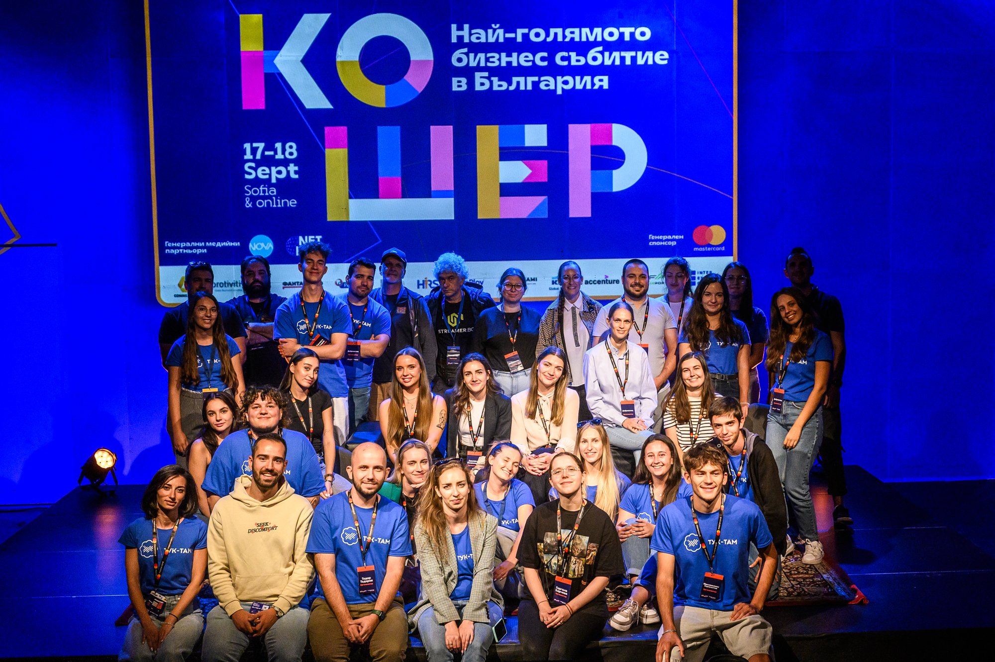 Wide-angle photograph of a large group of people posing on a stage.
