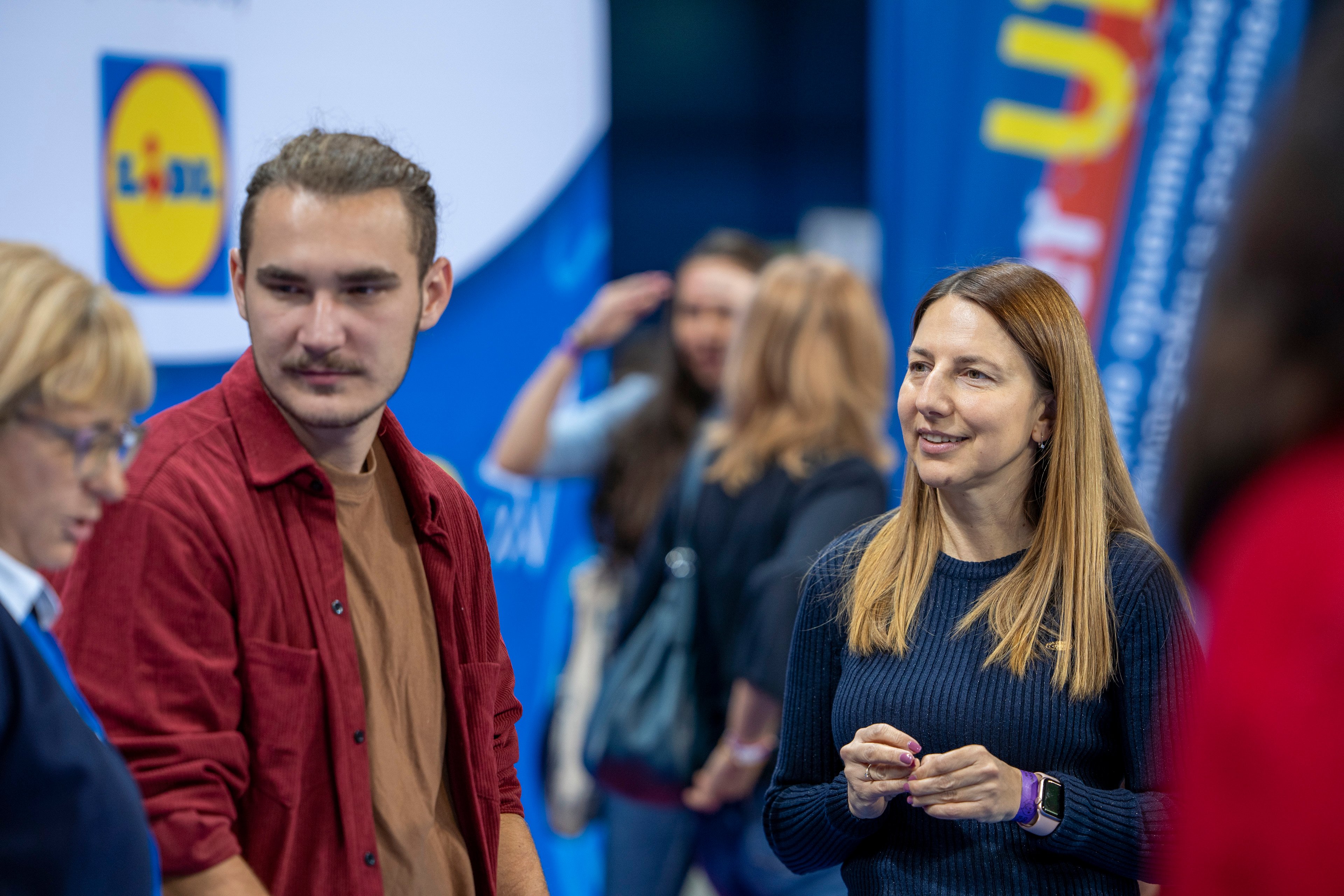 Two women talk at a minimart booth.