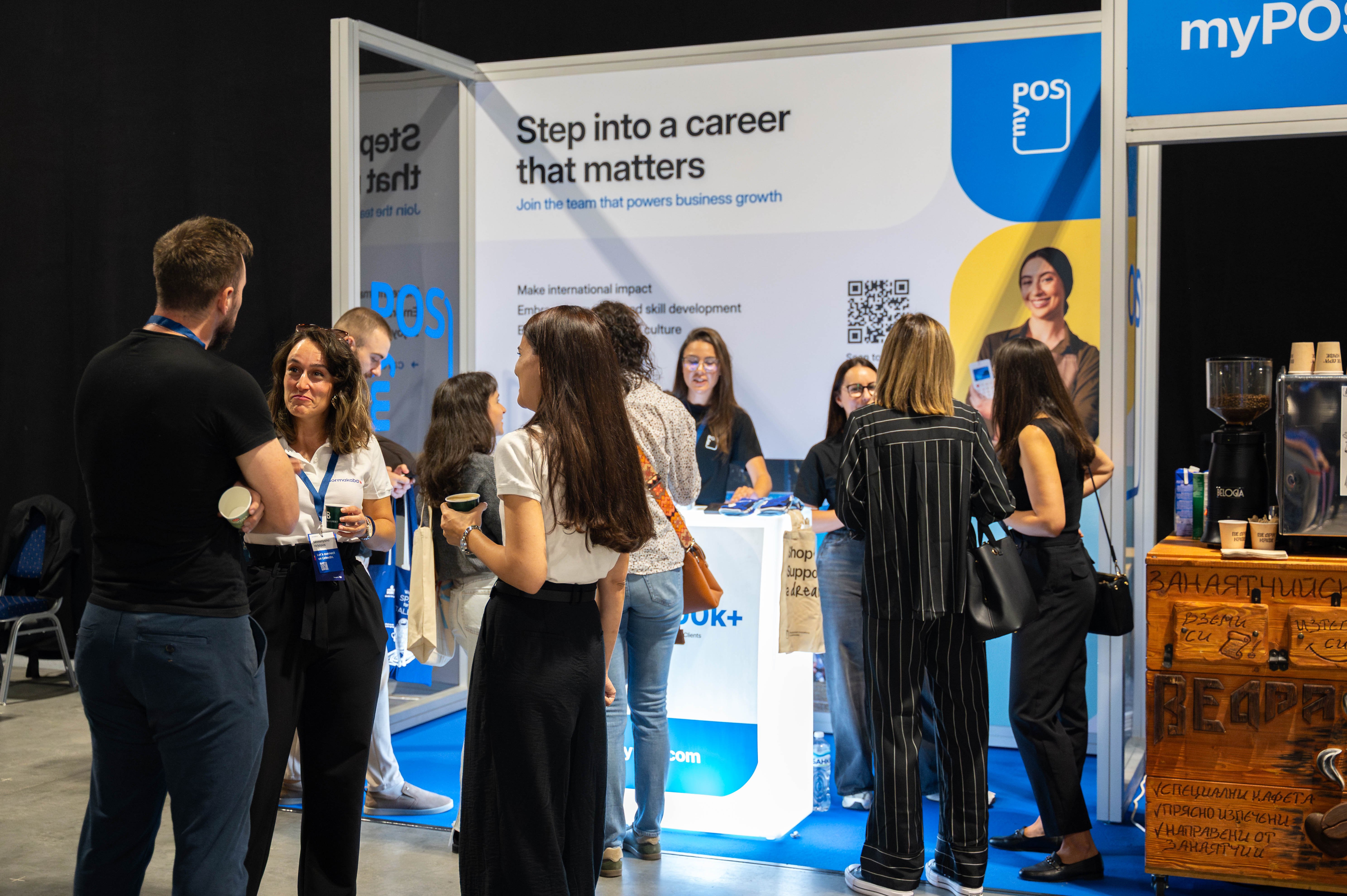 People gathered at a myPOS career booth with a sign reading ‘Step into a career that matters.’